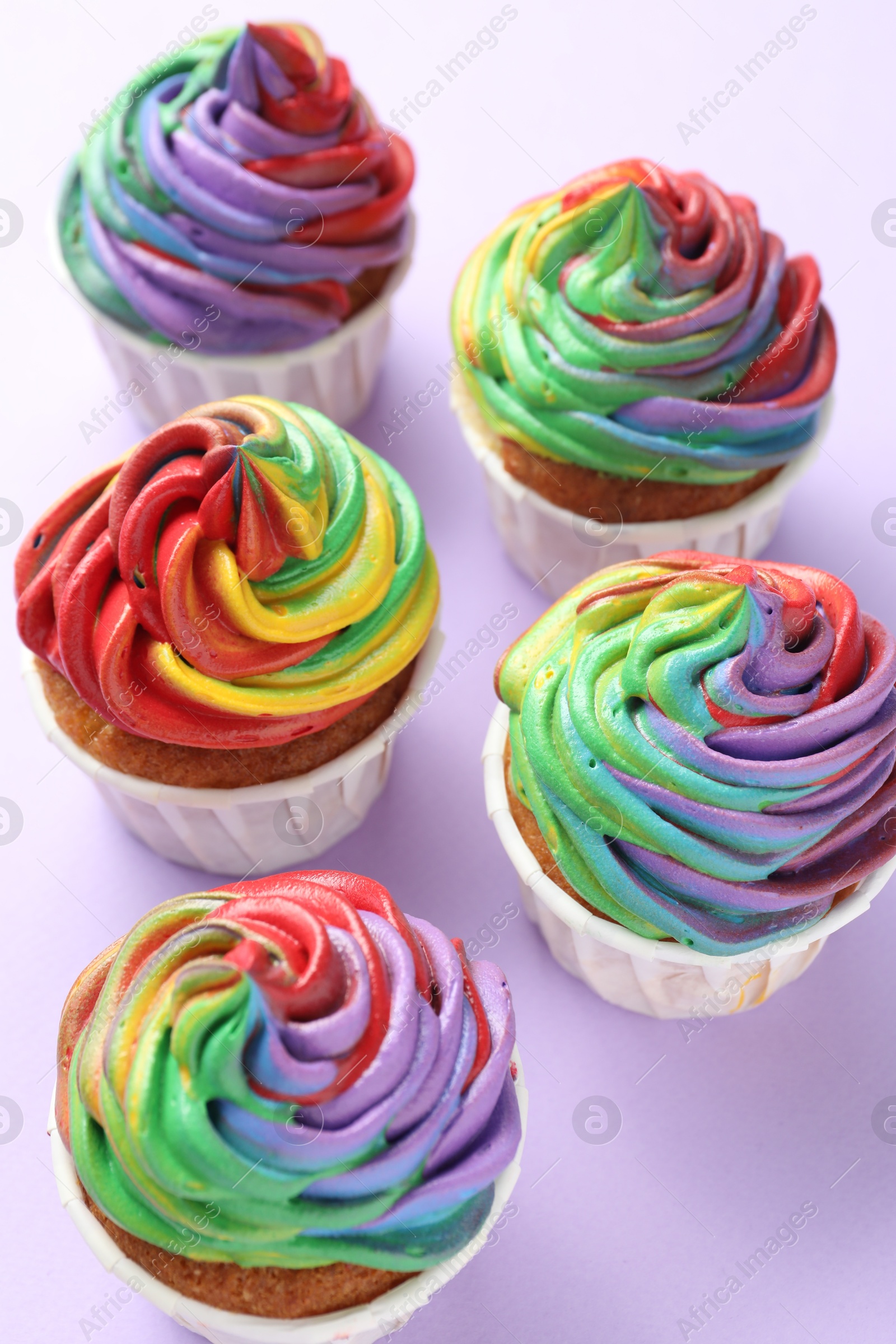 Photo of Delicious cupcakes with colorful cream on violet background