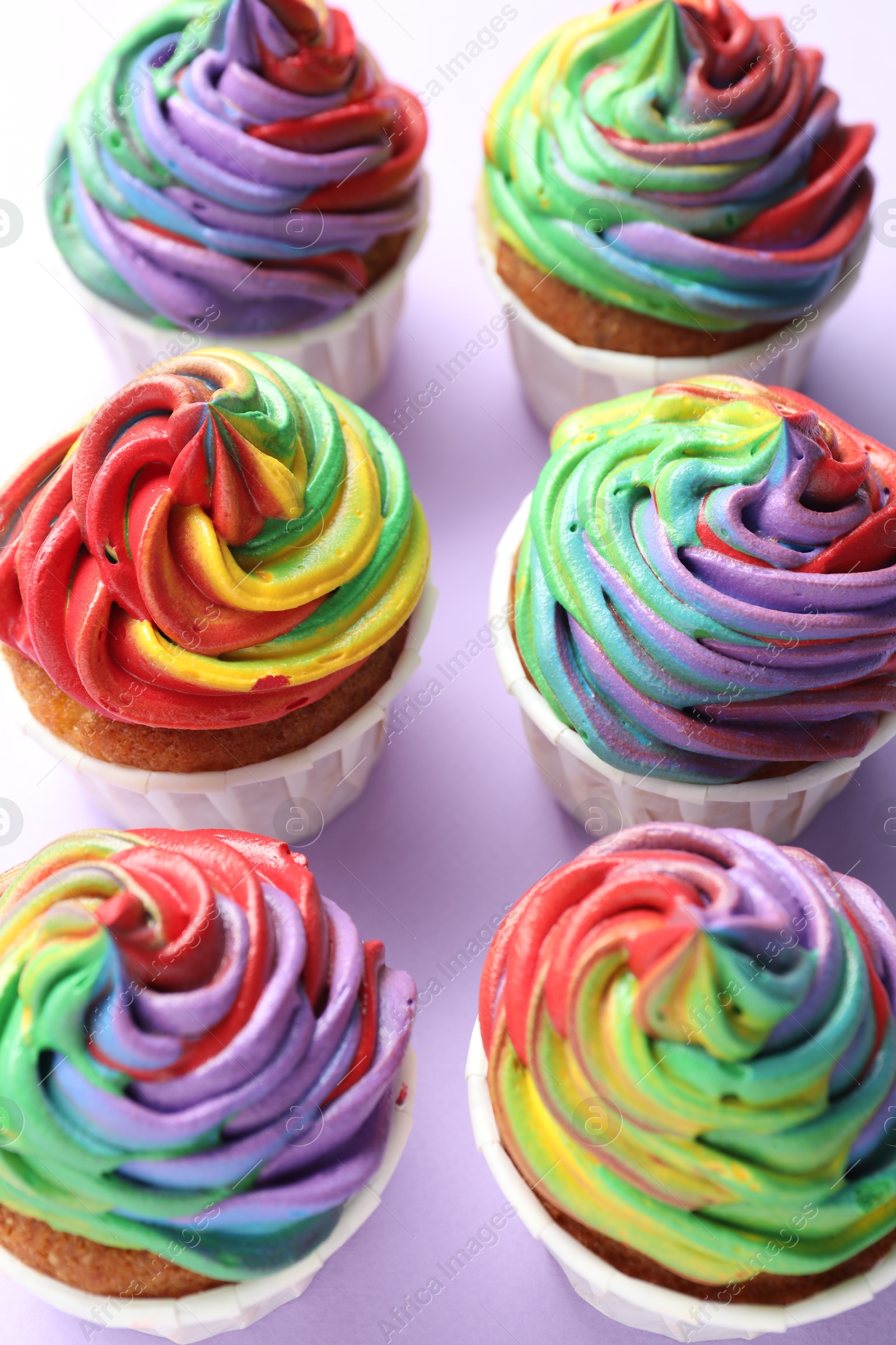 Photo of Delicious cupcakes with colorful cream on violet background