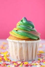 Photo of Delicious cupcake with colorful cream and confetti on light table, closeup. Space for text