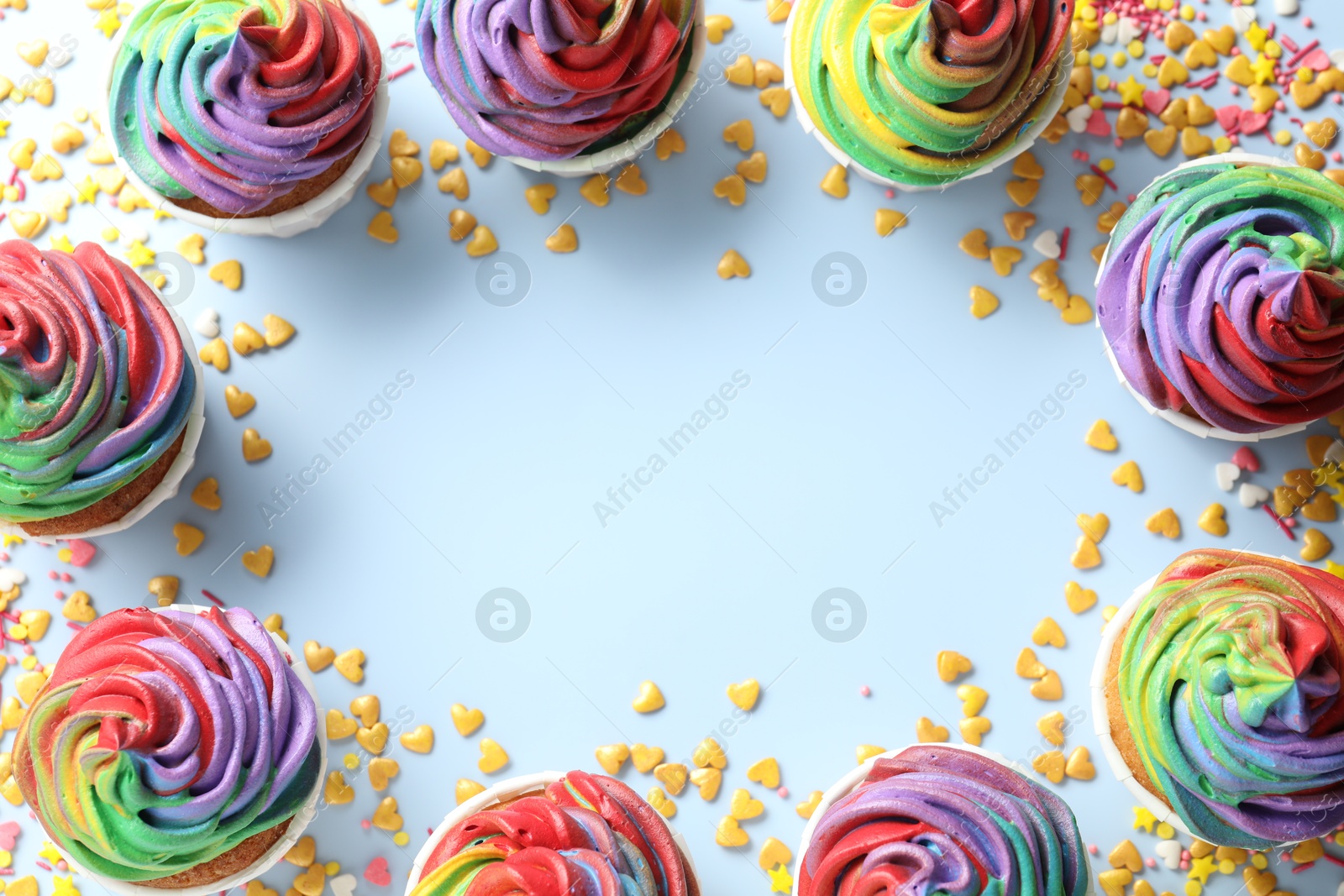 Photo of Frame of delicious cupcakes with colorful cream and confetti on light table, flat lay. Space for text