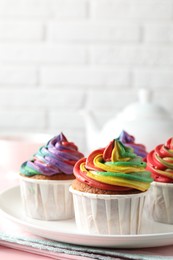 Photo of Delicious cupcakes with colorful cream and tea on pink table, closeup. Space for text