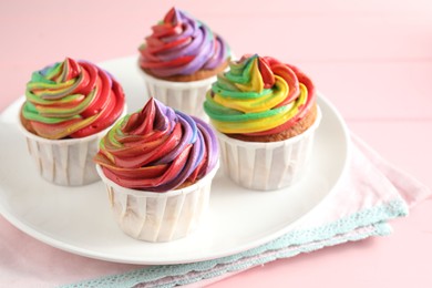 Photo of Delicious cupcakes with colorful cream on pink table, closeup