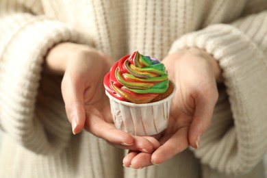 Photo of Woman holding delicious cupcake with colorful cream, closeup