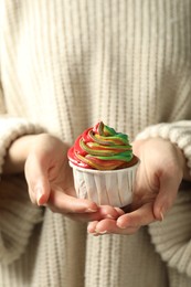 Photo of Woman holding delicious cupcake with colorful cream, closeup