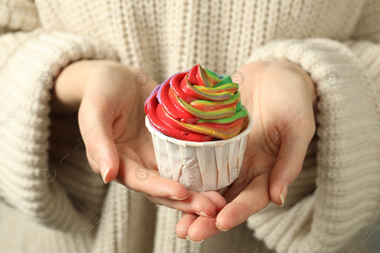 Photo of Woman holding delicious cupcake with colorful cream, closeup