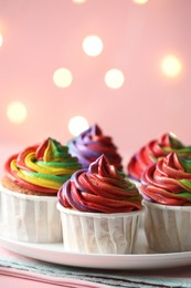 Photo of Delicious cupcakes with colorful cream on table against pink background, closeup and space for text. Bokeh effect