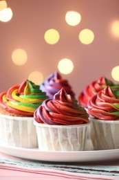 Photo of Delicious cupcakes with colorful cream on table against pink background, closeup and space for text. Bokeh effect