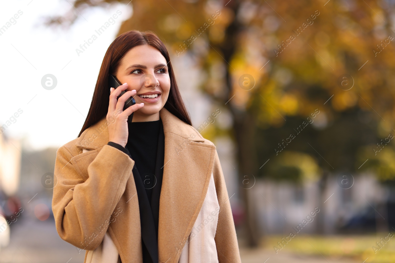 Photo of Smiling businesswoman in stylish outfit talking on smartphone outdoors. Space for text