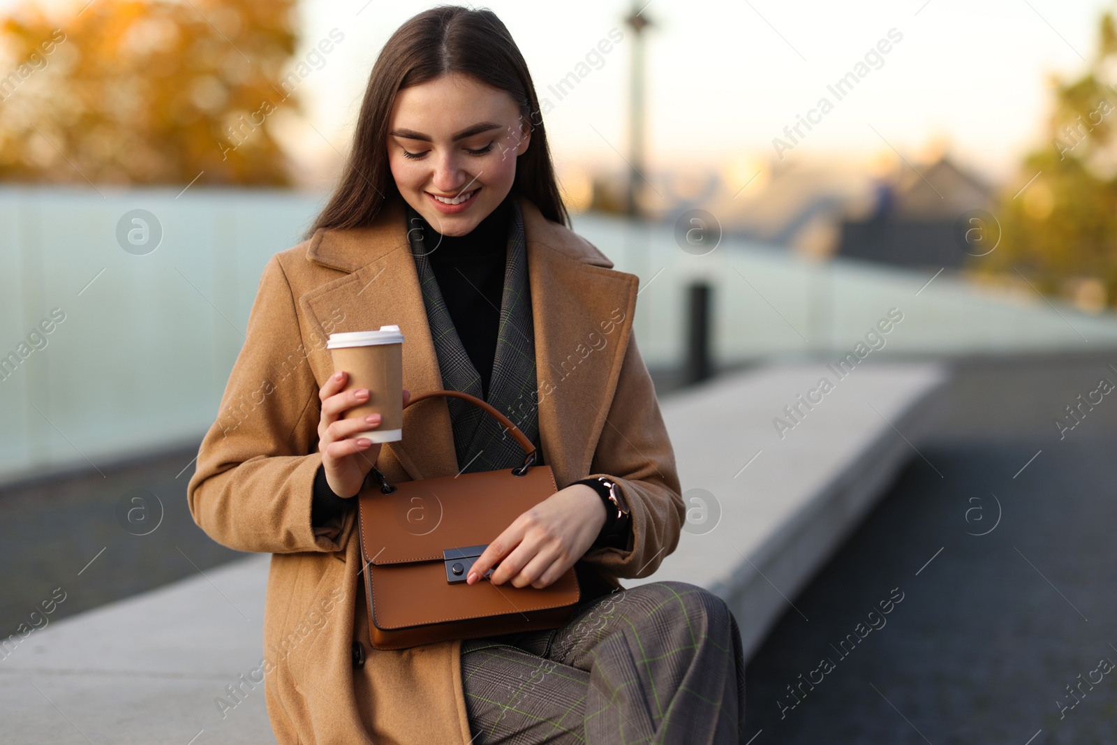 Photo of Beautiful woman in stylish suit with paper cup outdoors. Space for text