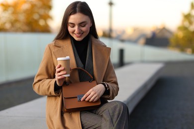 Photo of Beautiful woman in stylish suit with paper cup outdoors. Space for text