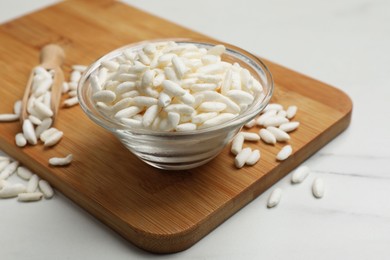 Photo of Puffed rice in bowl on white marble table, closeup