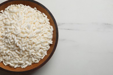 Photo of Puffed rice in bowl on white marble table, top view. Space for text