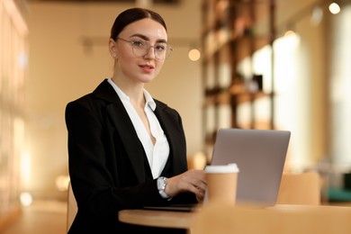 Photo of Woman in stylish formal suit working on laptop at table indoors