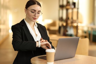 Photo of Woman in stylish formal suit working on laptop at table indoors