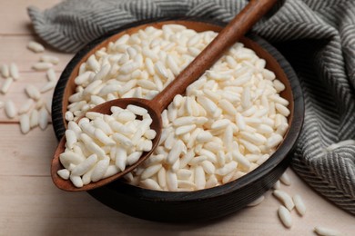 Photo of Puffed rice in bowl and spoon on white wooden table, closeup