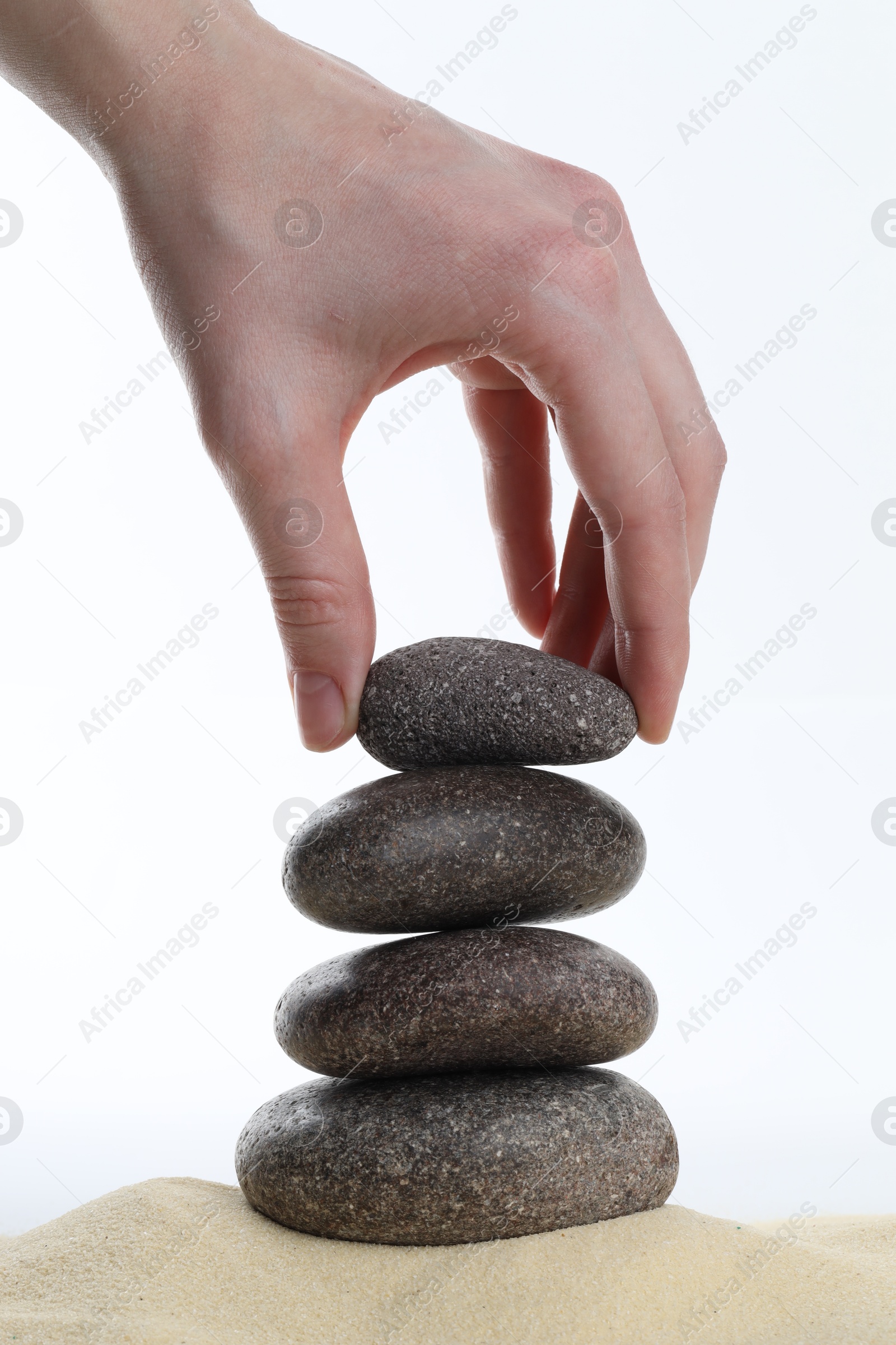 Photo of Woman making stack of stones on white background, closeup. Harmony and life balance