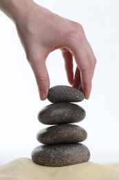 Photo of Woman making stack of stones on white background, closeup. Harmony and life balance