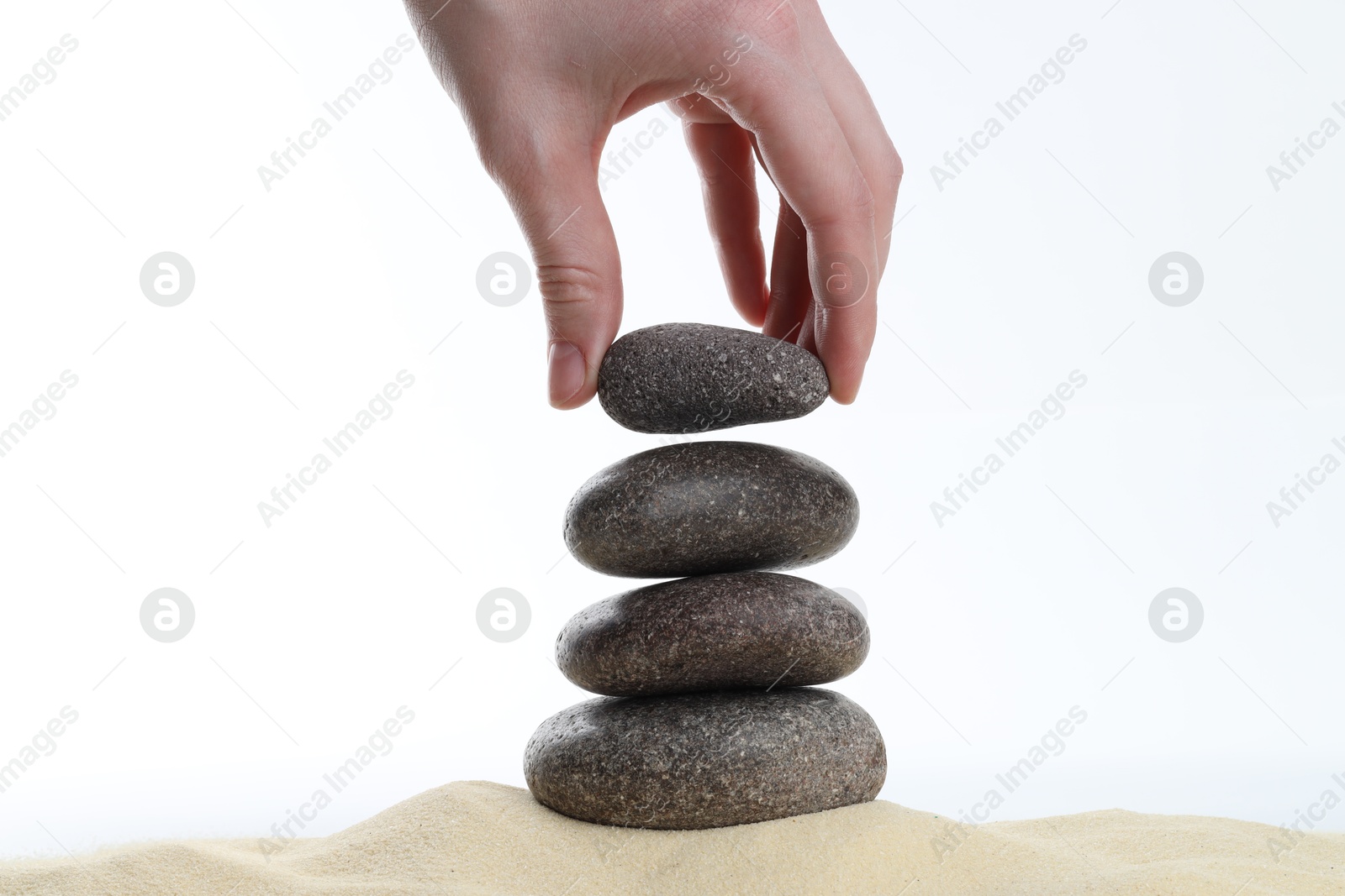 Photo of Woman making stack of stones on white background, closeup. Harmony and life balance