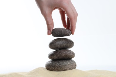 Photo of Woman making stack of stones on white background, closeup. Harmony and life balance