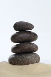 Photo of Stack of rocks on sand against white background. Harmony and life balance