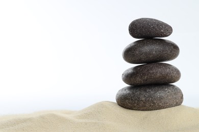 Photo of Stack of rocks on sand against white background, space for text. Harmony and life balance