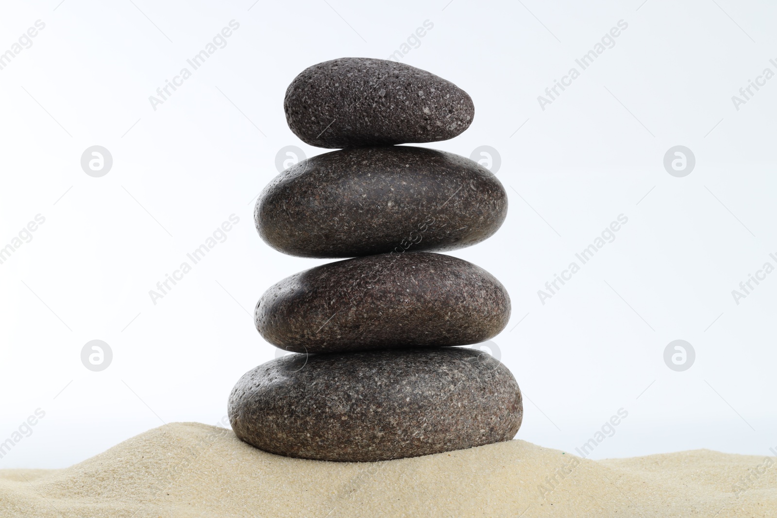 Photo of Stack of rocks on sand against white background. Harmony and life balance