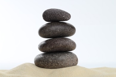 Photo of Stack of rocks on sand against white background. Harmony and life balance