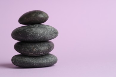 Photo of Stack of rocks on lilac background, space for text. Harmony and life balance