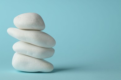 Photo of Stack of rocks on light blue background, space for text. Harmony and life balance