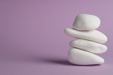 Photo of Stack of rocks on violet background, space for text. Harmony and life balance