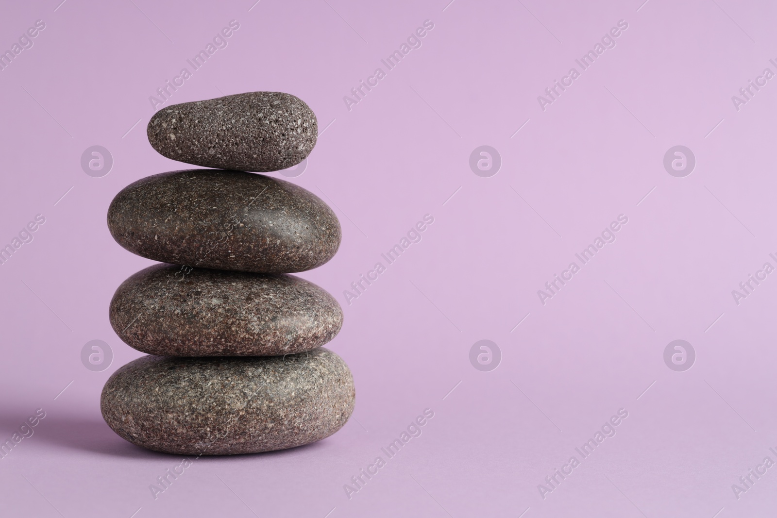 Photo of Stack of rocks on lilac background, space for text. Harmony and life balance