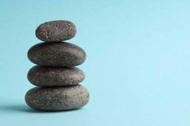 Photo of Stack of rocks on light blue background, space for text. Harmony and life balance