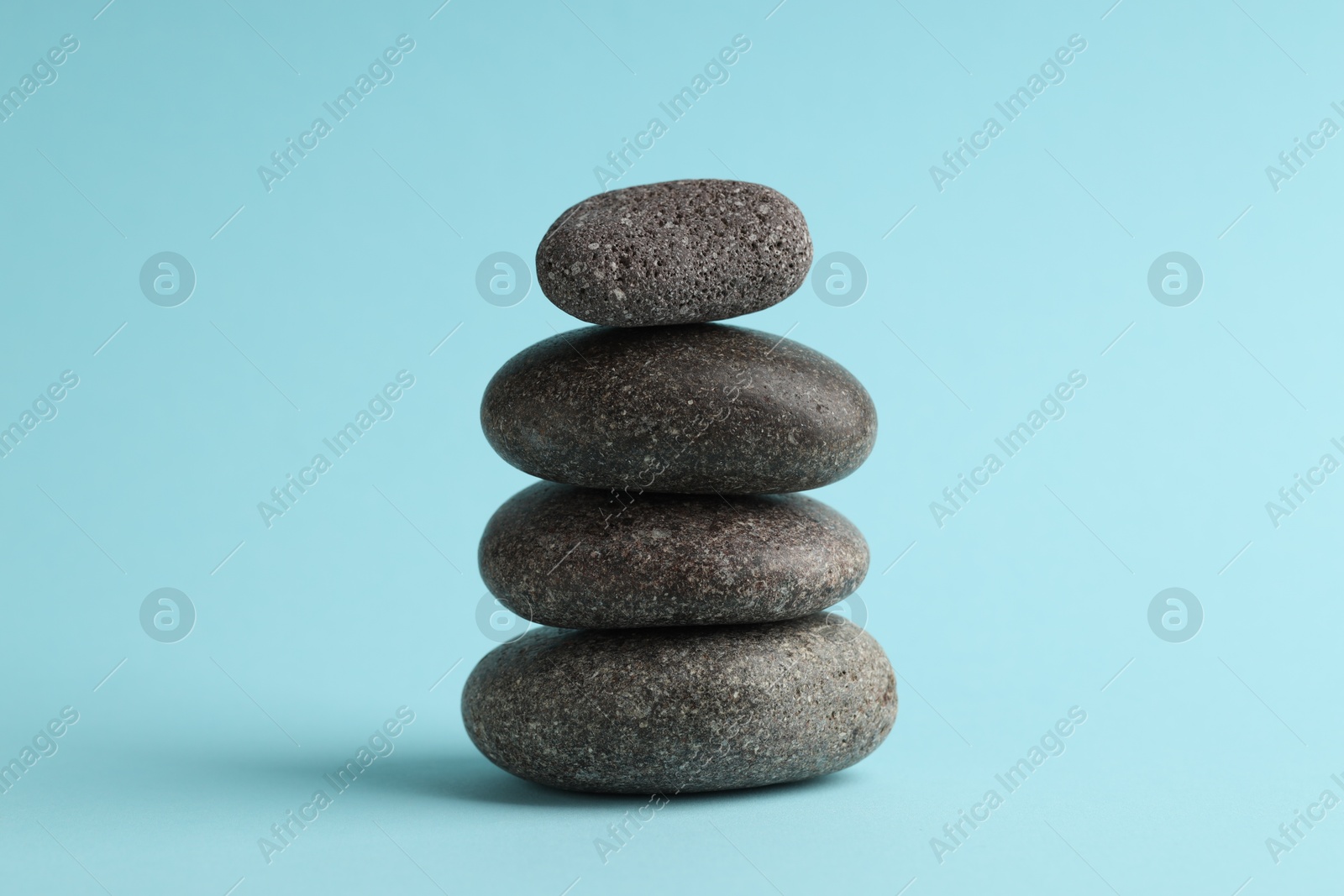 Photo of Stack of rocks on light blue background. Harmony and life balance