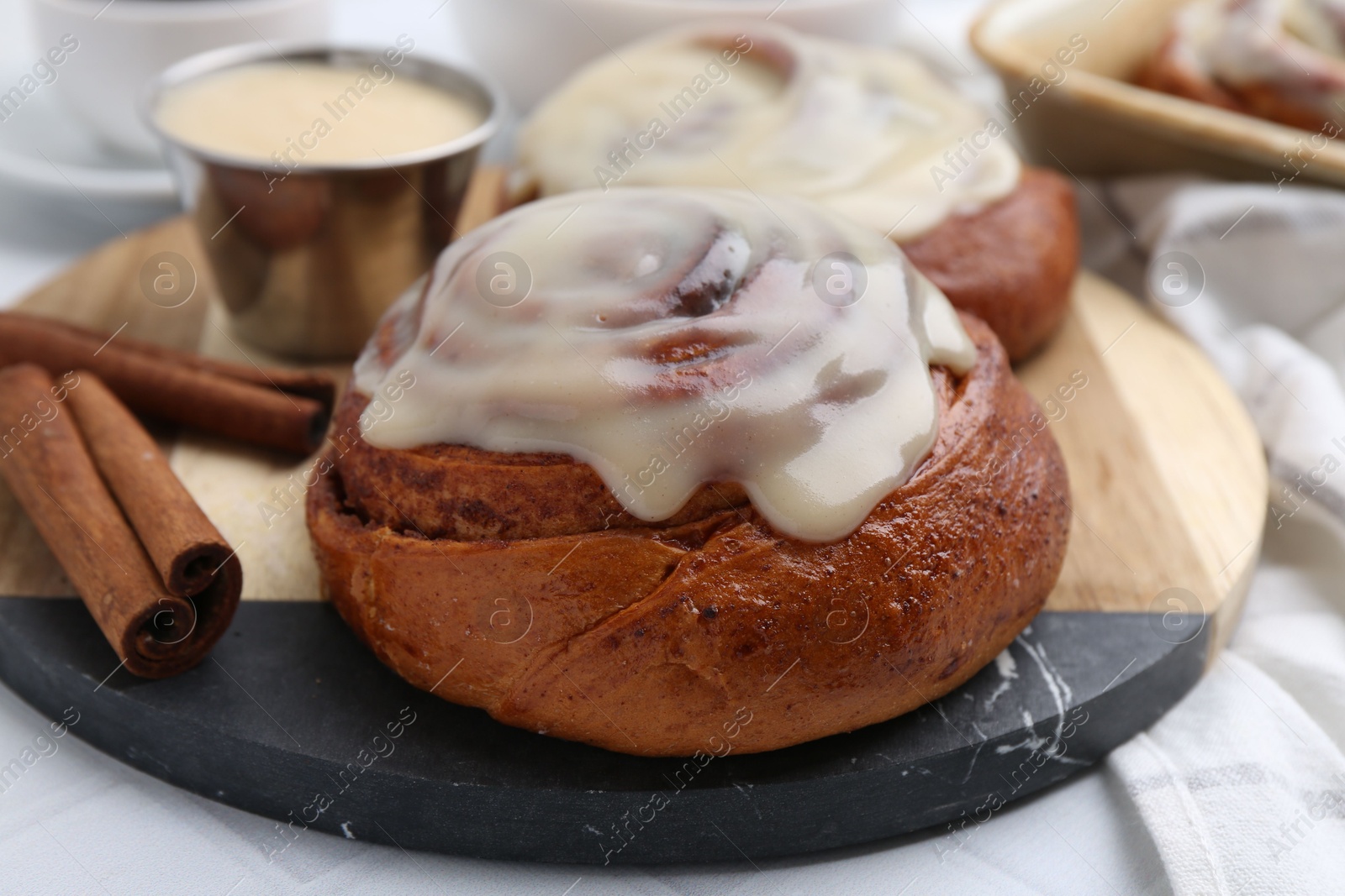 Photo of Tasty cinnamon rolls with cream and spices on table, closeup