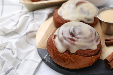 Photo of Tasty cinnamon rolls with cream and spices on table, closeup. Space for text