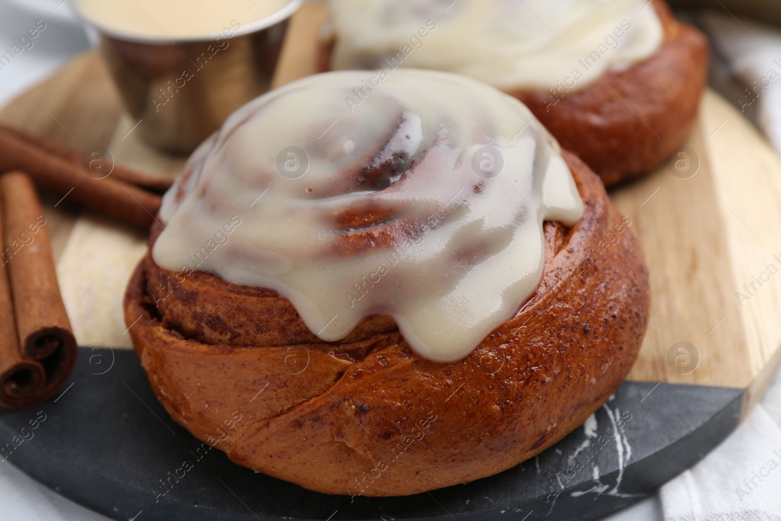 Photo of Tasty cinnamon rolls with cream and spices on table, closeup