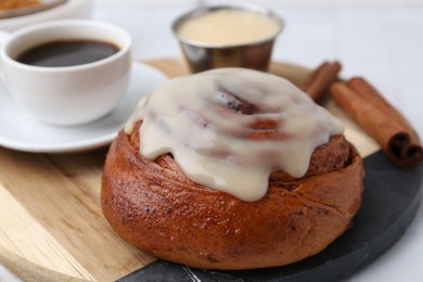 Photo of Tasty cinnamon roll with cream, spices and coffee on table, closeup