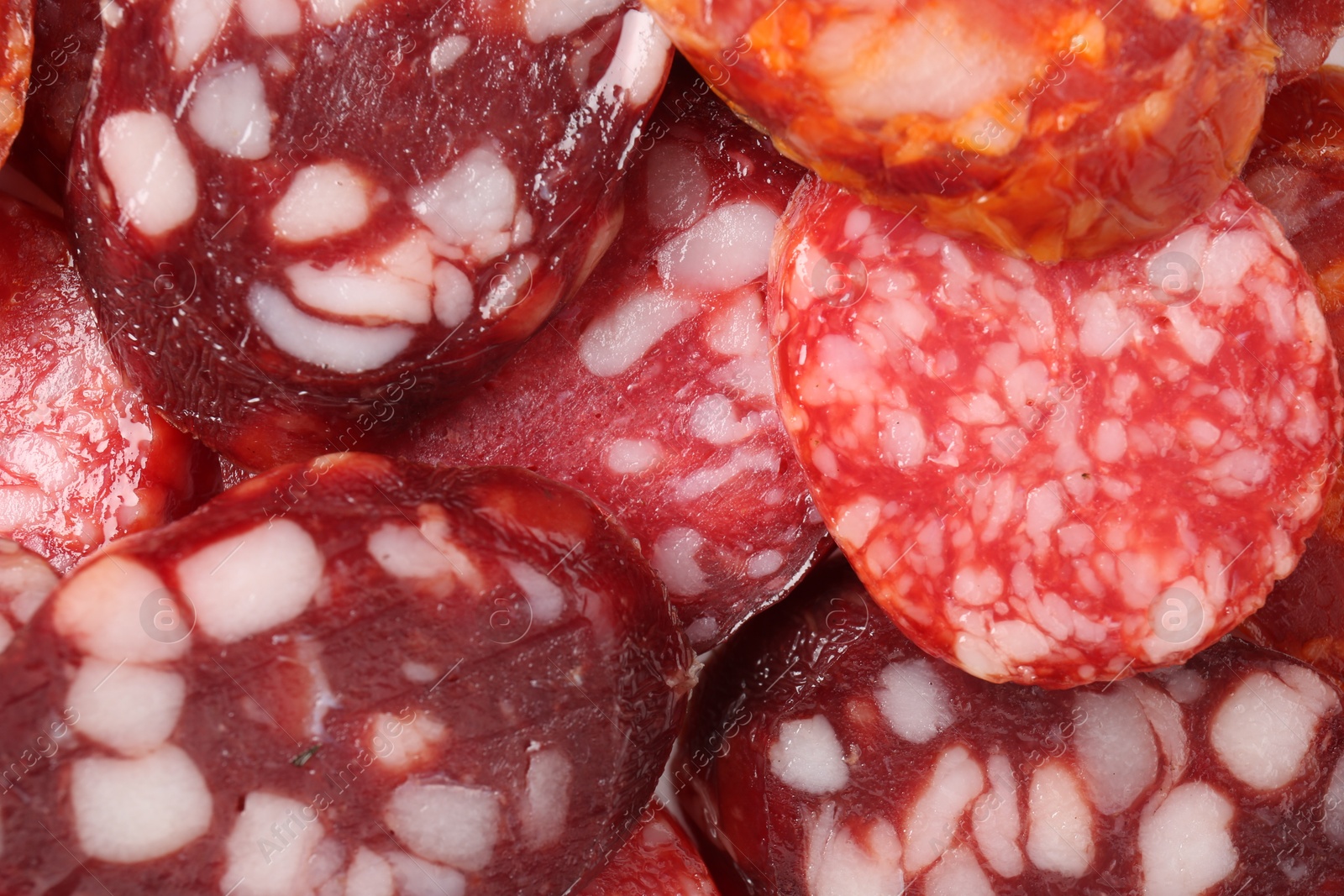 Photo of Pieces of different tasty smoked sausages as background, top view