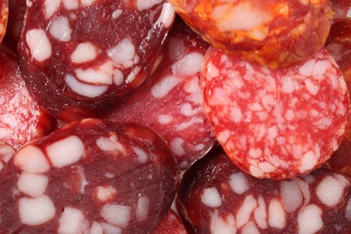 Photo of Pieces of different tasty smoked sausages as background, top view