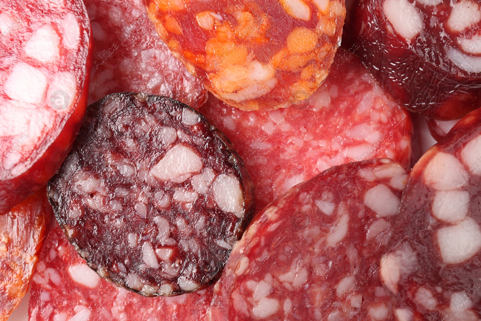 Photo of Pieces of different tasty smoked sausages as background, top view