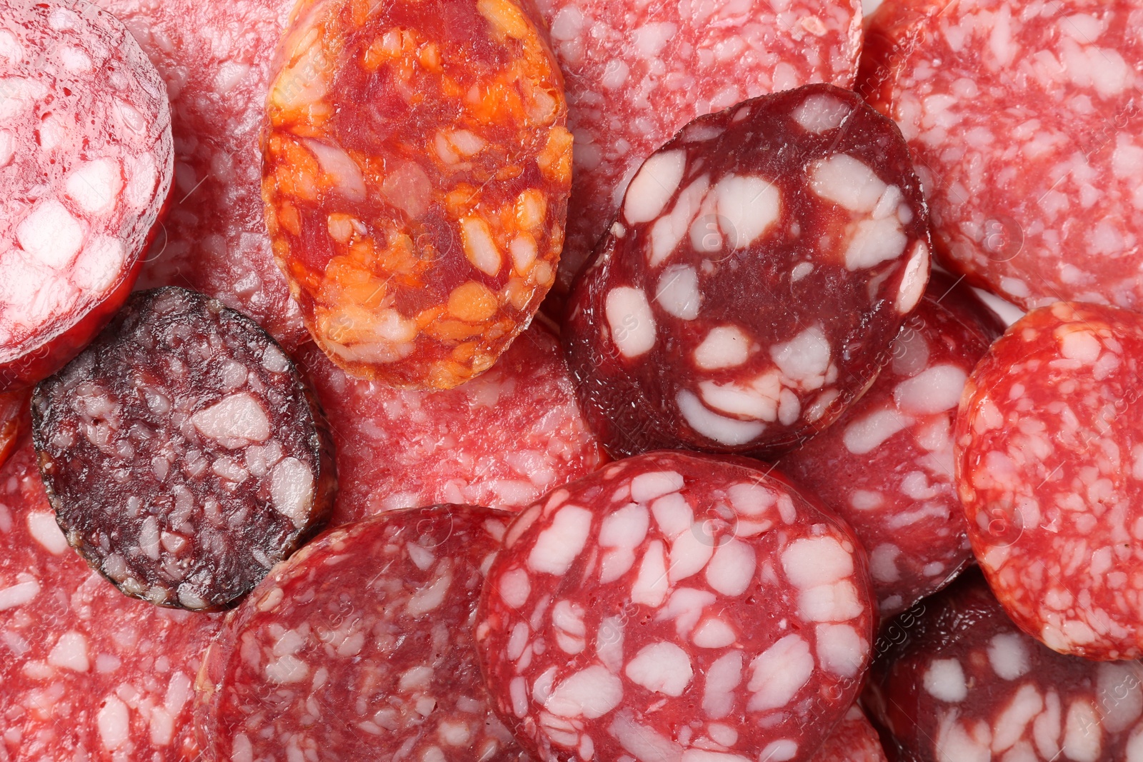 Photo of Pieces of different tasty smoked sausages as background, top view