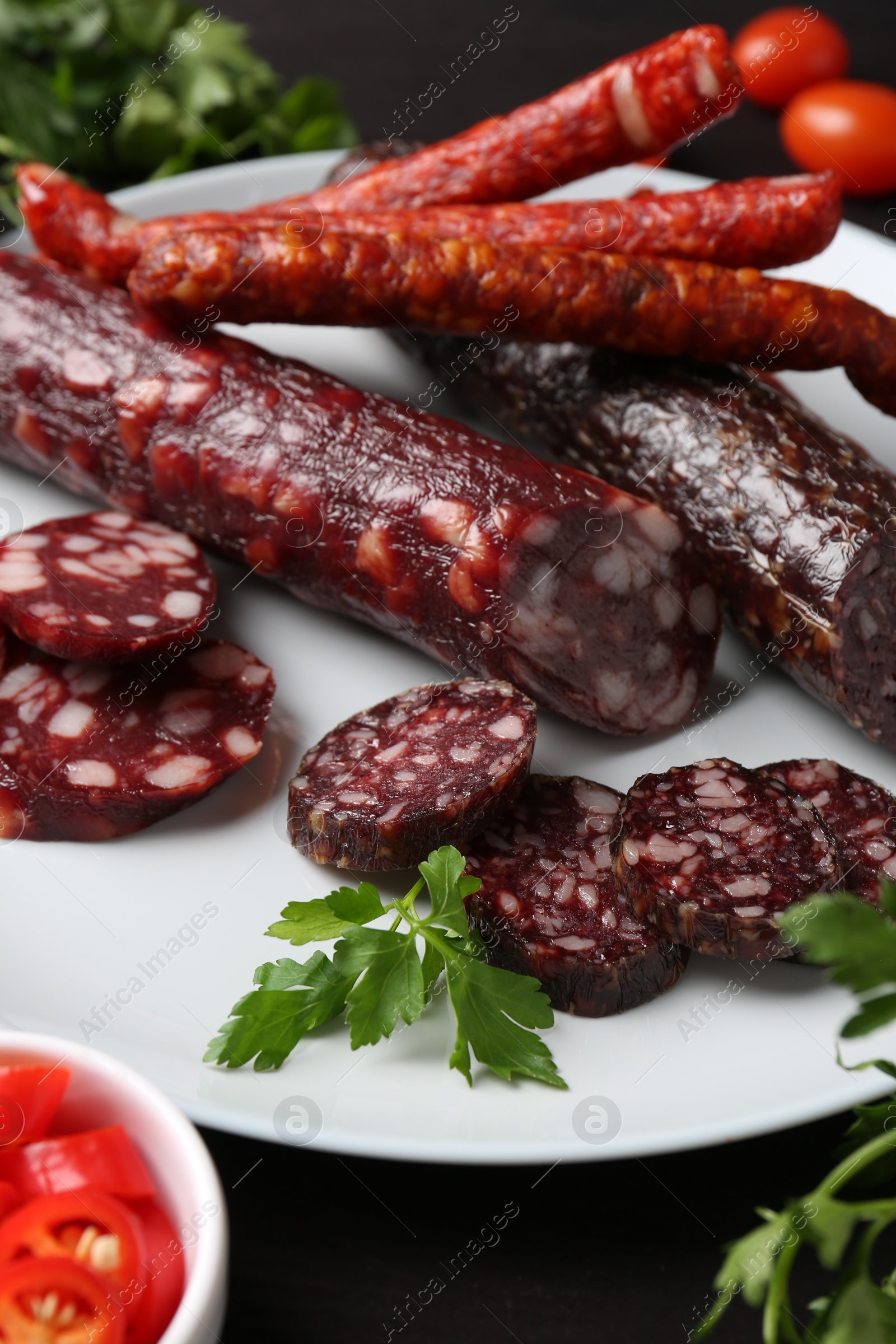 Photo of Different smoked sausages and spices on table, closeup