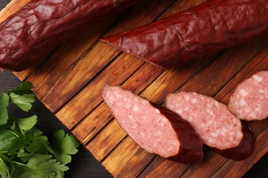 Photo of Delicious thin smoked sausage and parsley on table, top view