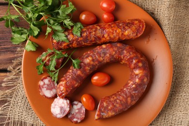 Photo of Different smoked sausages, cherry tomatoes and parsley on wooden table, top view