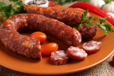 Photo of Different smoked sausages, cherry tomatoes and spices on table, closeup