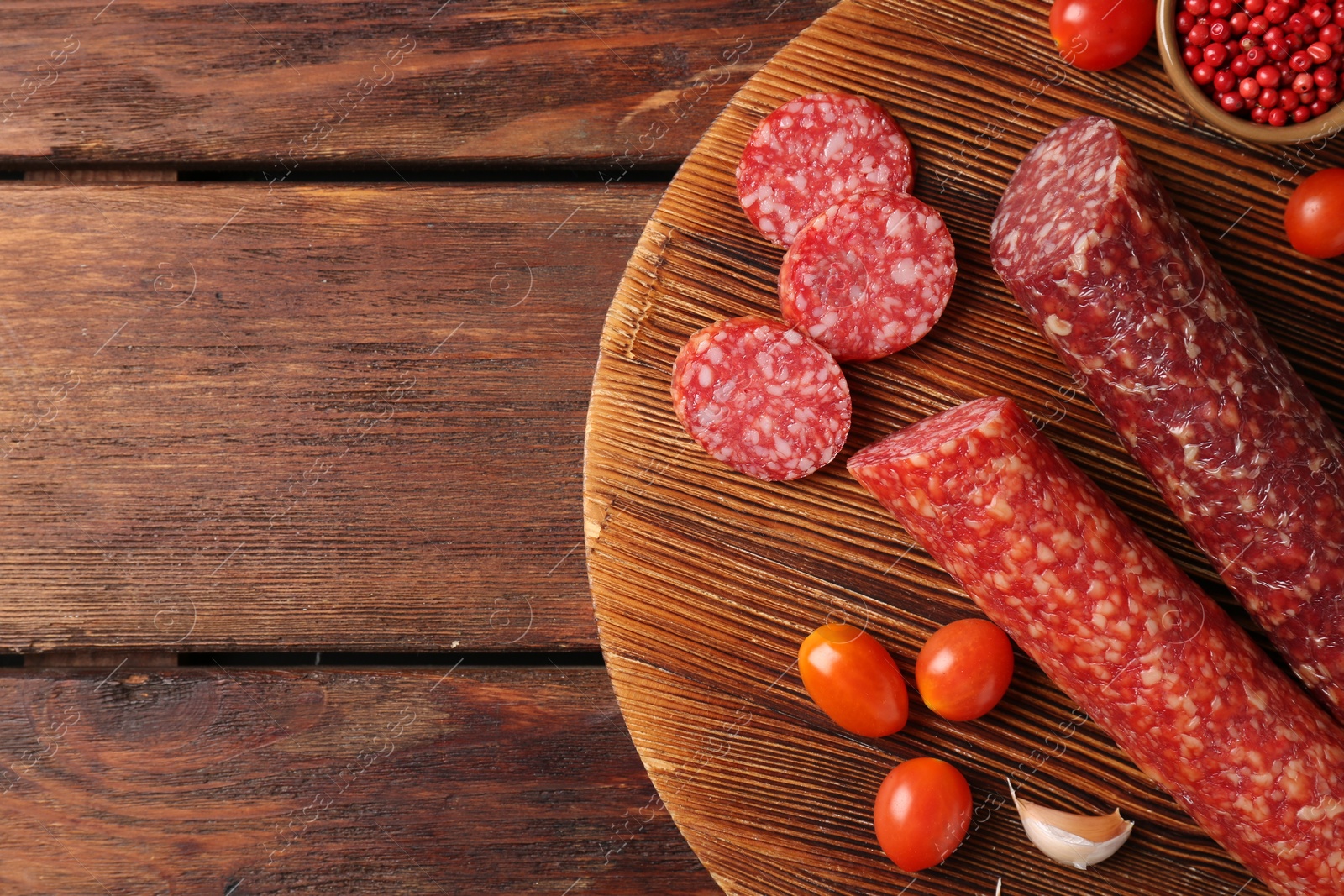 Photo of Different smoked sausages, cherry tomatoes and spices on wooden table, top view. Space for text