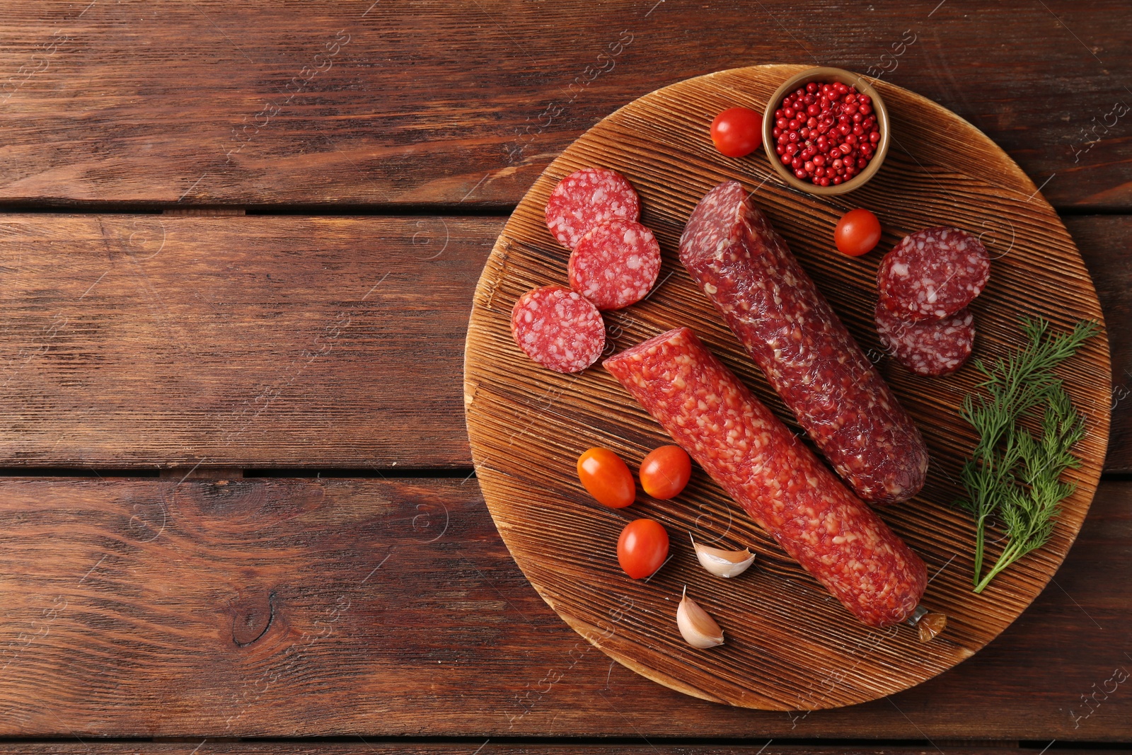 Photo of Different smoked sausages, cherry tomatoes and spices on wooden table, top view. Space for text