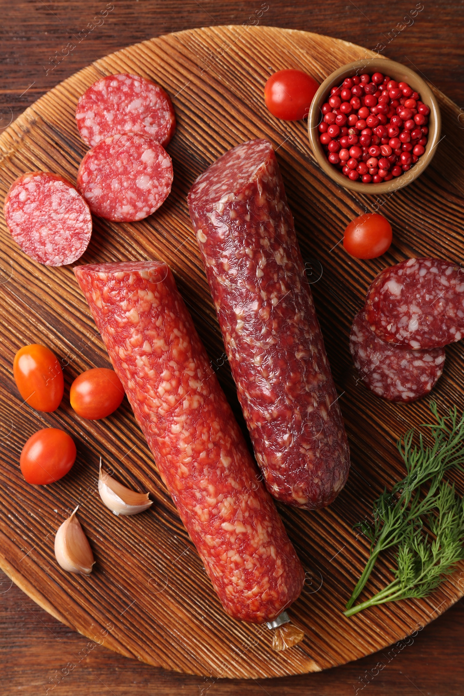 Photo of Different smoked sausages, cherry tomatoes and spices on wooden table, top view