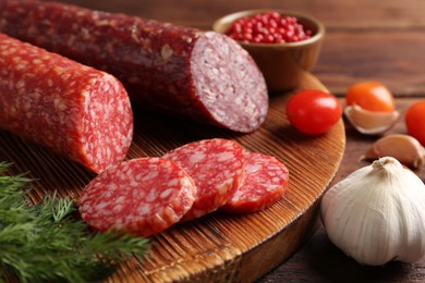 Photo of Different smoked sausages, cherry tomatoes and spices on table, closeup