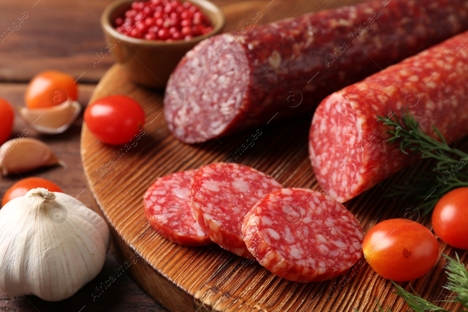 Photo of Different smoked sausages, cherry tomatoes and spices on table, closeup